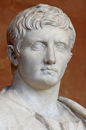 Buste en marbre de l'empereur romain Auguste représenté de trois quarts avec la chevelure bouclée traditionnelle et les yeux vides.