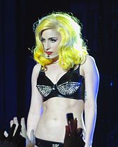 A woman with yellow hair, wearing a black bikini-shaped outfit.