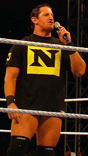 Wade Barrett, leader du Nexus, parle au public dans un micro. Il porte un T-shirt frappé du symbole du Nexus.
