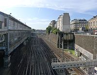 Les voies et la gare vues respectivement de la place de l'Europe (à gauche) et du boulevard des Batignolles (à droite).