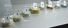 Photo de huit boites de conserve, rondes et de faible hauteur, numérotées.