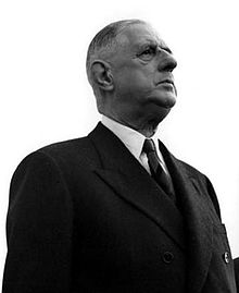 Photographie en noir et blanc, prise en contre-plongée et de droite, de Charles de Gaulle, vêtu d'un costume noir. Le cadrage de l'image rend le sujet impressionnant.