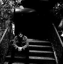 Photographie de Carmine Appice assis sur les marches d'un perron.