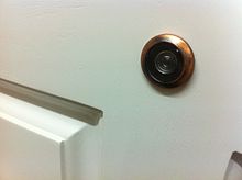 Un petit trou rond vitré cerné de métal dans un porte