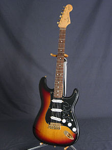 Photographie d'une guitare Fender stratocaster signée Stevie Ray Vaughan, sur un porte guitare.