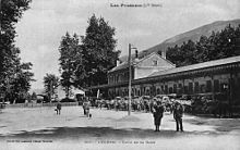La cour extérieure de la gare, avec le bâtiment voyageurs et les voitures et omnibus en attente, vers 1900
