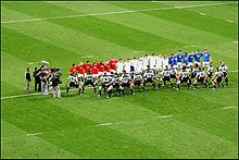McCaw et les Néo-Zélandais en maillot gris interprètent le haka face aux joueurs français vêtus de bleu, blanc et rouge.