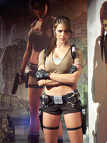 Femme portant un short marron et un t-shirt de la même couleur, devant un panneau publicitaire