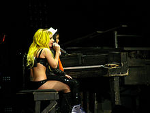 Gaga assise sur un tabouret de piano alors qu'une jeune fille est posée sur ses genoux.