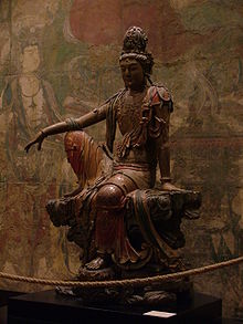 La statue représente un Bodhisattva assis sur un banc. Sa jambe droite est posée sur le plateau du banc et sa main droite repose sur son genou droit. Le Bodhisattva assure sa stabilité avec sa main gauche, posée sur le banc.