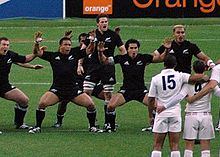 McCaw au centre du haka néo-zélandais fait face à une rangée de joueurs français vêtus de blanc.