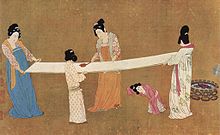 Quatre femmes sont en train de tendre un drap de soie blanche. L'une d'elles travaille le drap avec une brosse. Une petite fille observe la scène.