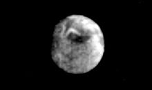 La lune Miranda vue entière et ronde par la sonde Voyager 2. Sa surface grise permet d'apercevoir le chevron blanc d'Inverness corona.
