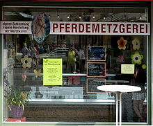 Devanture d'une boucherie avec une enseigne en forme de tete de cheval, suivie du mot "Pferdemetzger".