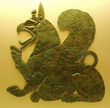 Plaque représentant un animal mi-lion et mi-aigle assis le bec ouvert.