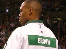 P. J. Brown de dos avec le survêtement blanc et vert des Celtics de Boston sur lequel est écrit son nom, Brown, en masjuscules.