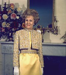 Pat Nixon posant dans une robe jaune, dans un salon de la Maison-Blanche.