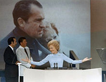 Pat Nixon à la tribune de la convention républicaine de 1972, (deux hommes et une affiche sont au second plan).