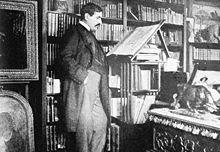 Paul Bourget dans son bureau, rue Barbet – de – Jouy, debout devant un pupitre.