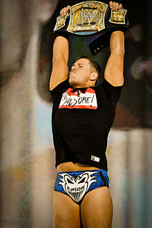 Photographie du catcheur The Miz. Il montre au public son titre de champion de la WWE.