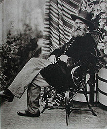 Photographie en noir et blanc de Tom Taylor, assis sur une chaise de jardin, prise par Lewis Carroll