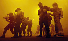 Sapeur-pompiers en train de combattre un feu fictif dans un local enfumé.