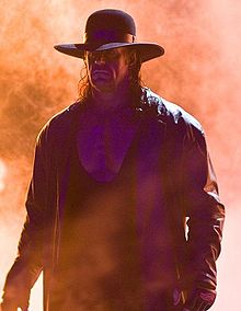 Photographie du catcheur (The) Undertaker. Des flammes (engins pyrotechniques) sont visibles en arrière-plan.