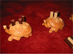 photographie en gros plan de deux tortues sculptées dans du bois. Le dos des tortues est percé de trous ronds dans lesquels sont posés des pions cylindriques de deux couleurs différentes