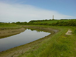 L’Adur, au nord-ouest de Shoreham-by-Sea, en regardant vers l’amont. La cheminée en arrière-plan est celle de la cimenterie abandonnée de Shoreham.
