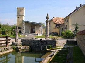 Le lavoir au premier plan, le calvaire et la fontaine au second plan, et l'église Saint-Gérard