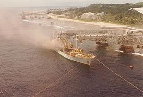 Vue aérienne du port d'Aiwo montrant les deux structures cantilever au moment du chargement d'un navire en phosphate. Le bassin, peu visible, est masqué par la deuxième structure cantilever.