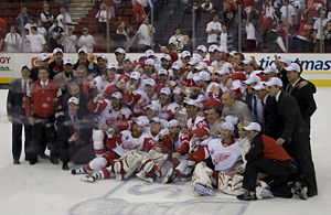 Photo de l'équipe et des dirigeants des Red Wings au centre de la patinoire, tous coiffés de la casquette de champion.