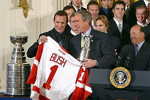 Photo de Yzerman à côté de la Coupe STanley et qui remet à Georges W. Bush un maillot des Red Wings avec le numéro 1 et son nom.