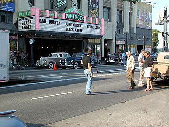  photo de tournage : voitures des années 1940 arrêtées devant un théâtre