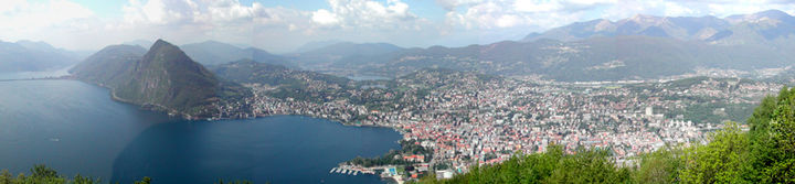 Photo panoramique de Lugano prise de « Monte brè » montrant à gauche: le lac, puis le « Monte San SAlvatore » qui marque l'entrée dans la crique autour de lqauelle s'étend la ville de Lugano